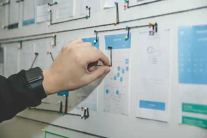 Organizing sticky notes on a wall for assumption mapping
